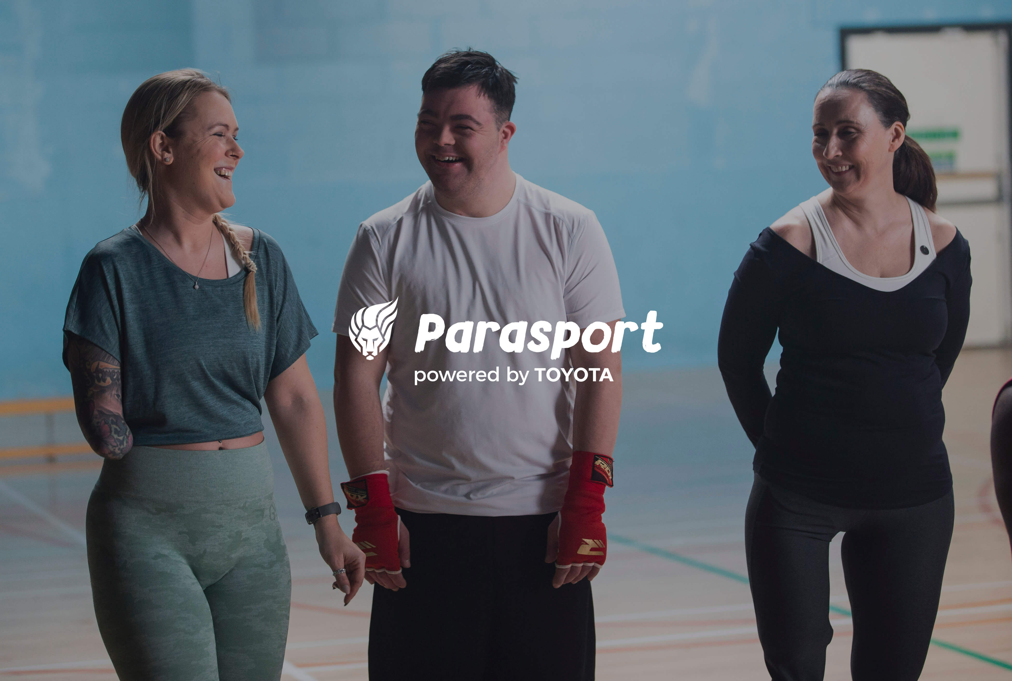 Image showing three young people ready to play sport. They have a range of impairments. They are laughing.